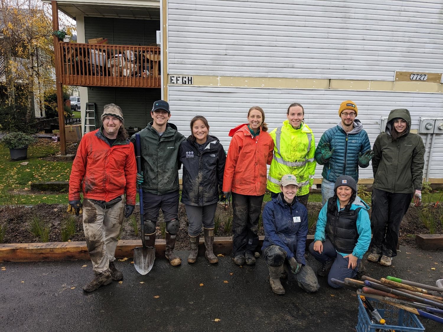Volunteers - muddy & happy - smiling for the camera after planting native plants all day in the rain.