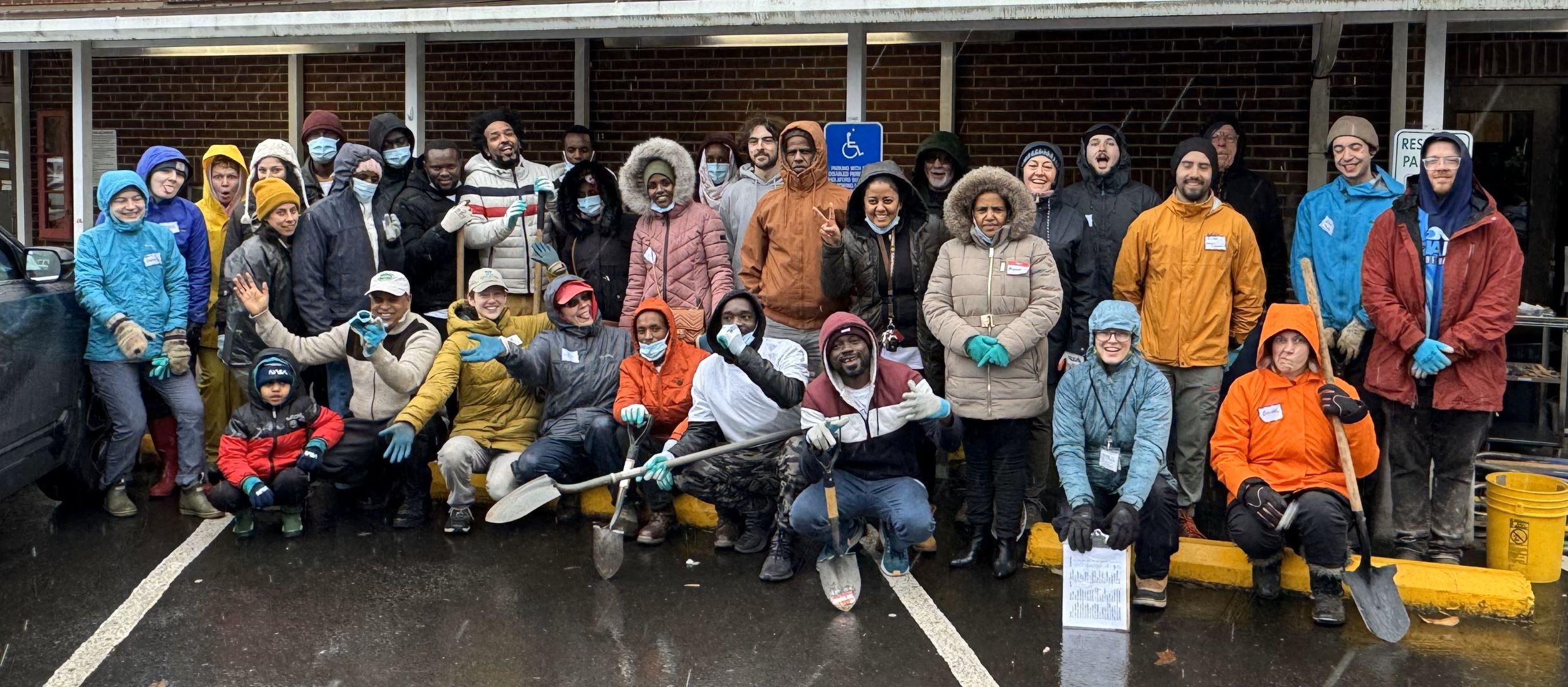 Volunteers and staff stand in front of a Trinity Lutheran Church in falling snow and rain gear. 
